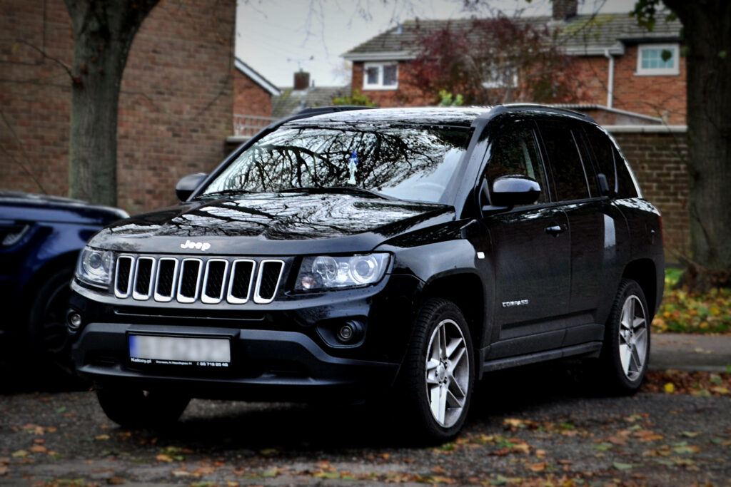 Black Jeep Compass parked under trees with autumn leaves perfect stylish nature wallpaper background