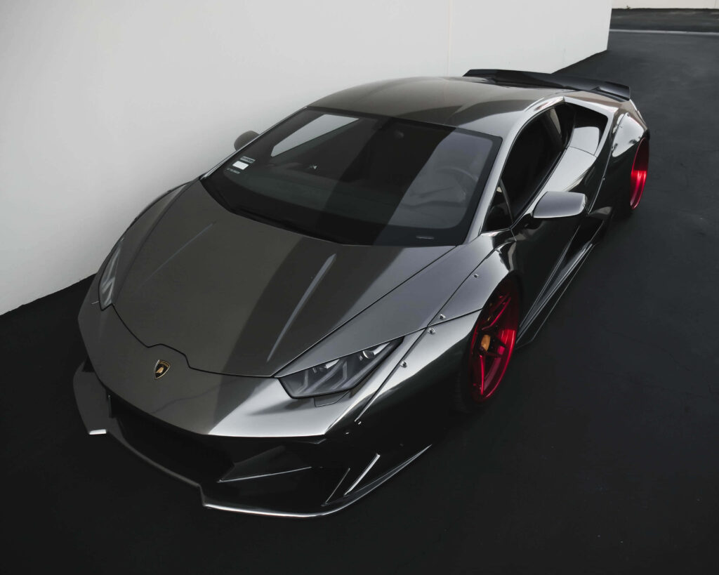 Black Lamborghini sports car with red rims against modern backdrop luxury car wallpaper background