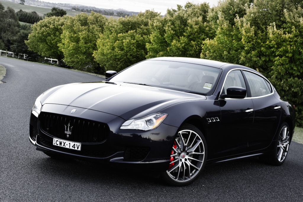 Sleek Black Maserati Quattroporte GTS Wallpaper with Lush Greenery