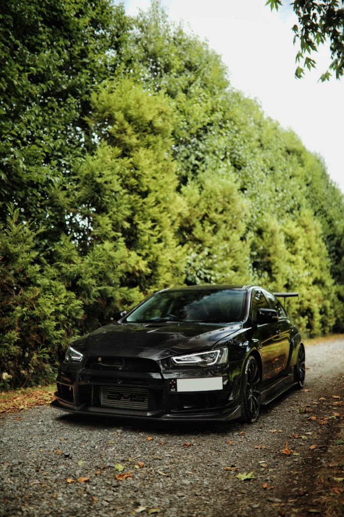 Sleek Black Mitsubishi Lancer Evolution Amidst Lush Greenery Wallpaper