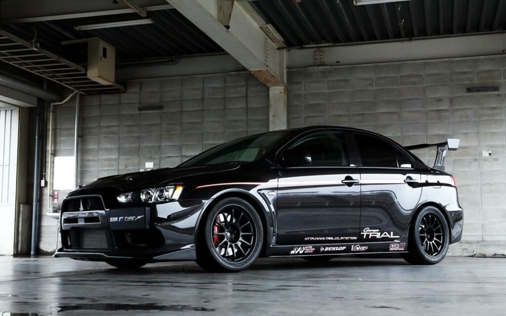 Sleek Black Mitsubishi Lancer Evolution Wallpaper in Industrial Setting