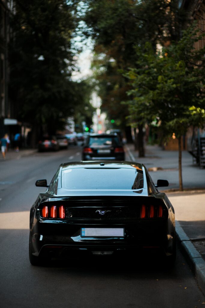 Rear View of Sleek Black Mustang with Illuminated Taillights at Dusk Wallpaper