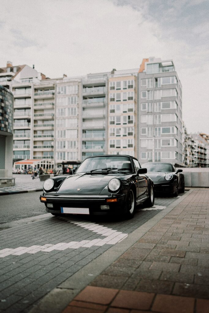 Sleek Black Porsche 911 in Urban High-Rise Setting - Car Enthusiasts Wallpaper