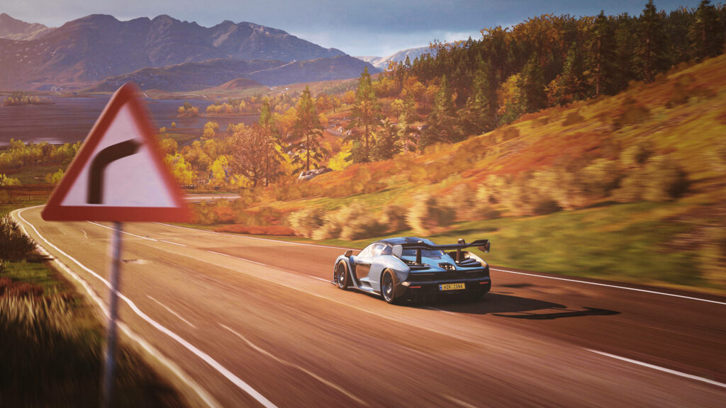 Black Porsche racing on autumn countryside road with mountains in Forza Horizon 4 wallpaper