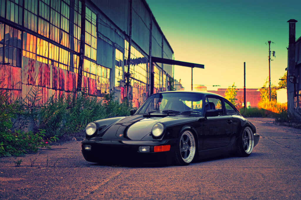 Sleek Black Porsche Against Stunning Industrial Sunset Backdrop Wallpaper