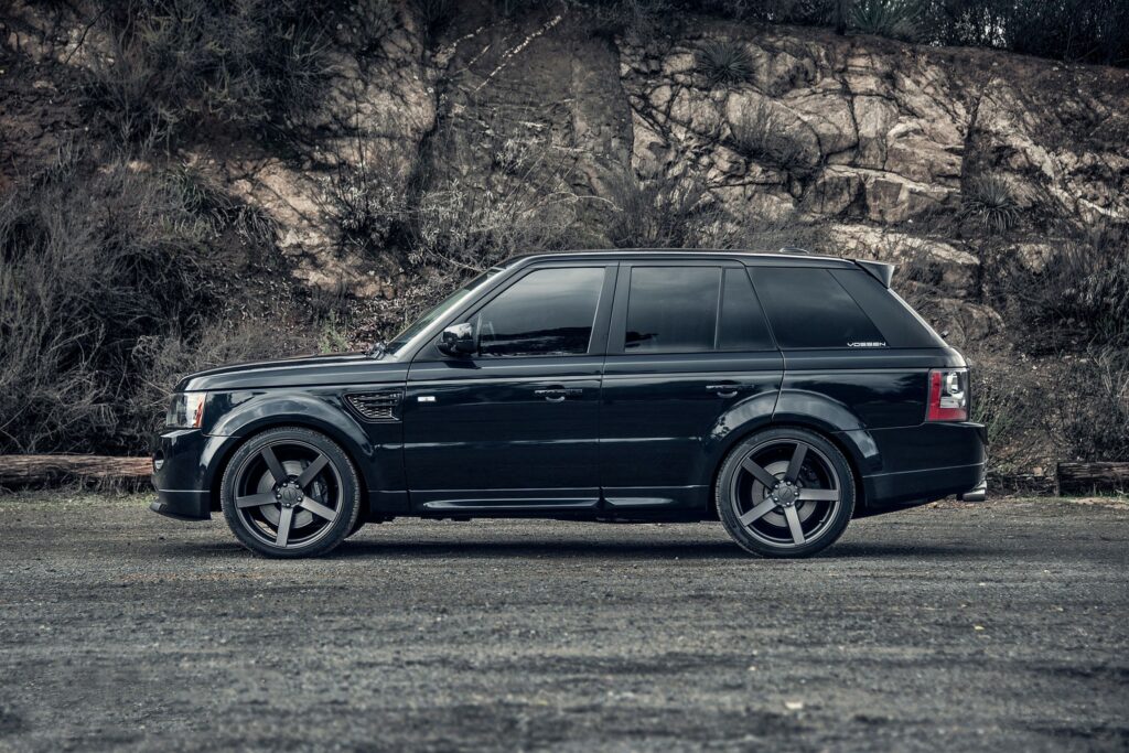 Sleek Black Range Rover Side View: Luxury in a Rugged Background Wallpaper