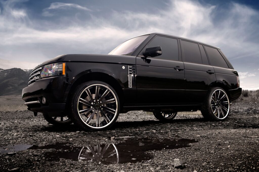 Sleek Black Range Rover on Rugged Terrain with Dramatic Clouds Wallpaper
