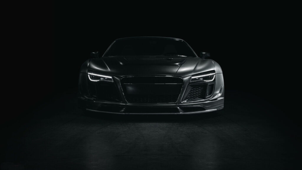 Sleek black sports car with sharp contours illuminated in dark background 4K Ultra HD wallpaper