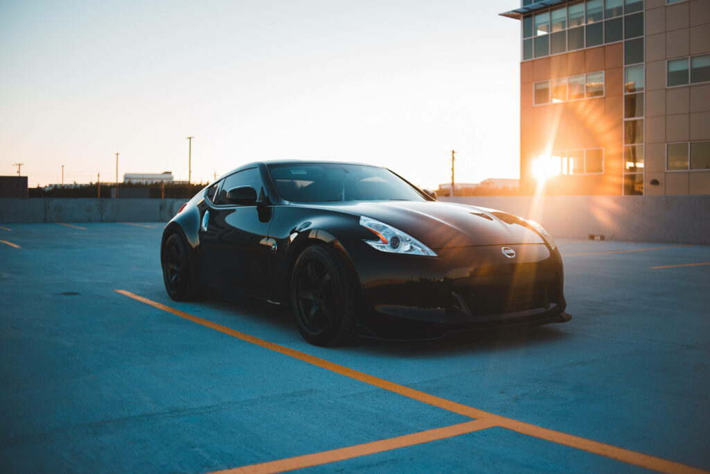 Black sports car on rooftop parking with sunset and modern building background wallpaper