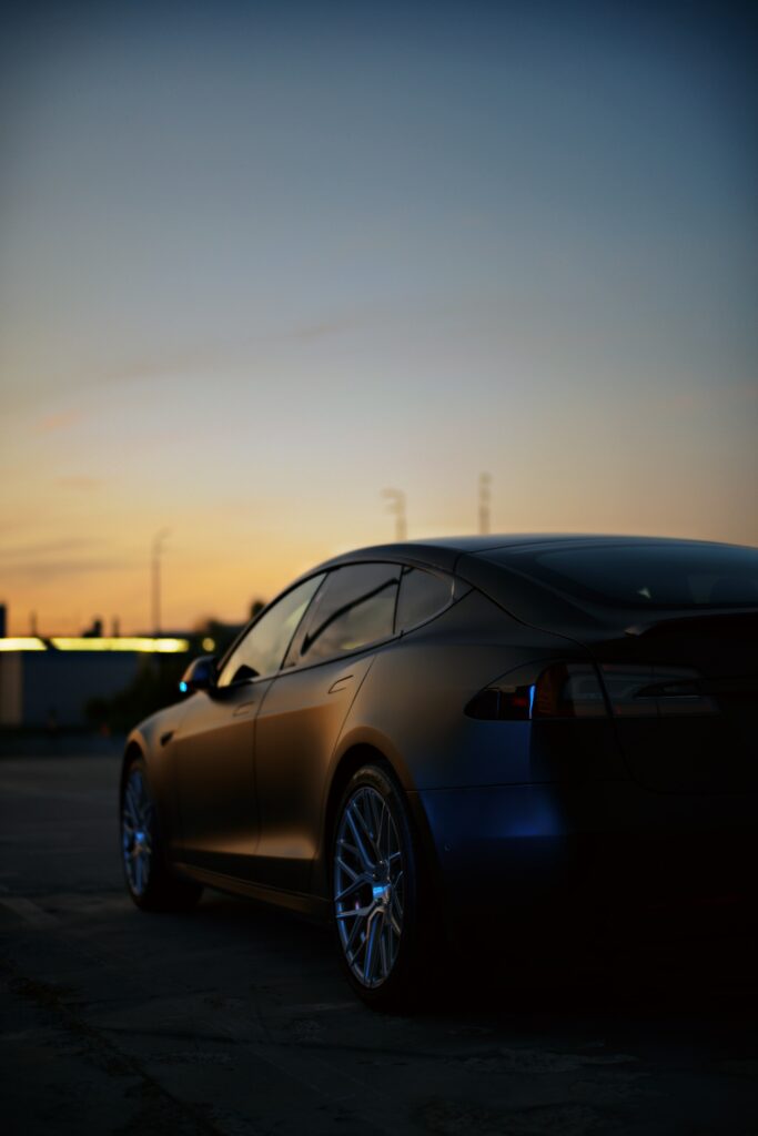 Sleek Black Tesla Car Wallpaper: Sunset Silhouette Background