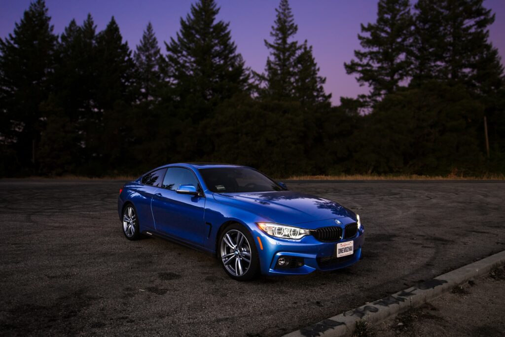 Sleek Blue Car Wallpaper - Twilight Skyline with Tall Trees