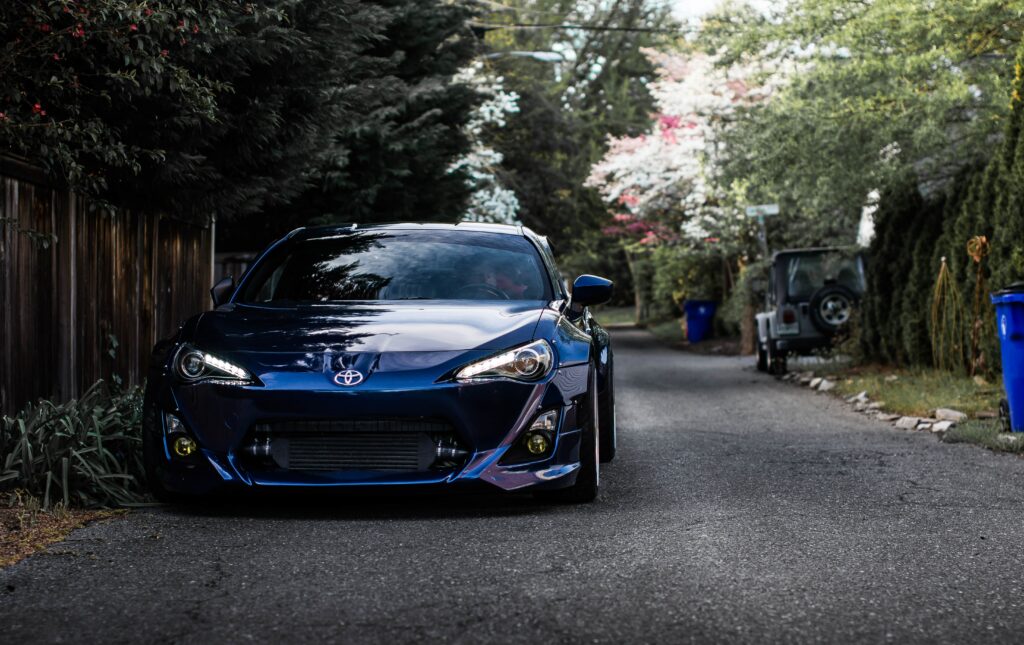 Sleek Blue Car on Tree-Lined Street - Stylish and Glossy Wallpaper