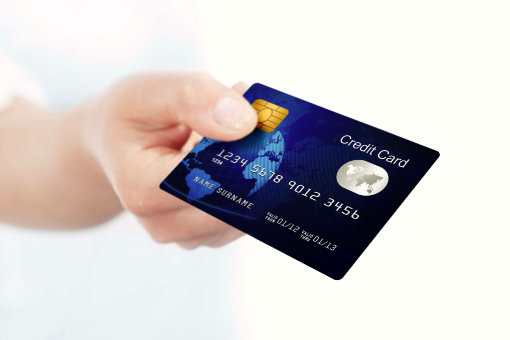 Hand holding sleek blue credit card with world map gold chip embossed numbers on white background Wallpaper