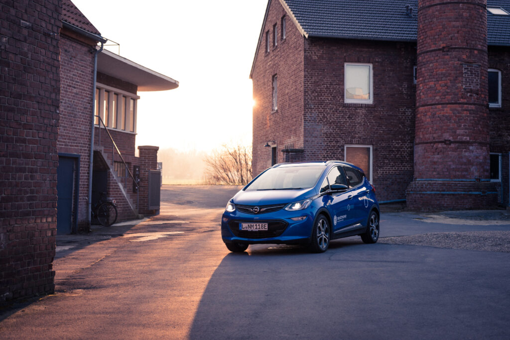 Stylish Blue Opel Ampera in Rustic Courtyard - Golden Sunlight Wallpaper