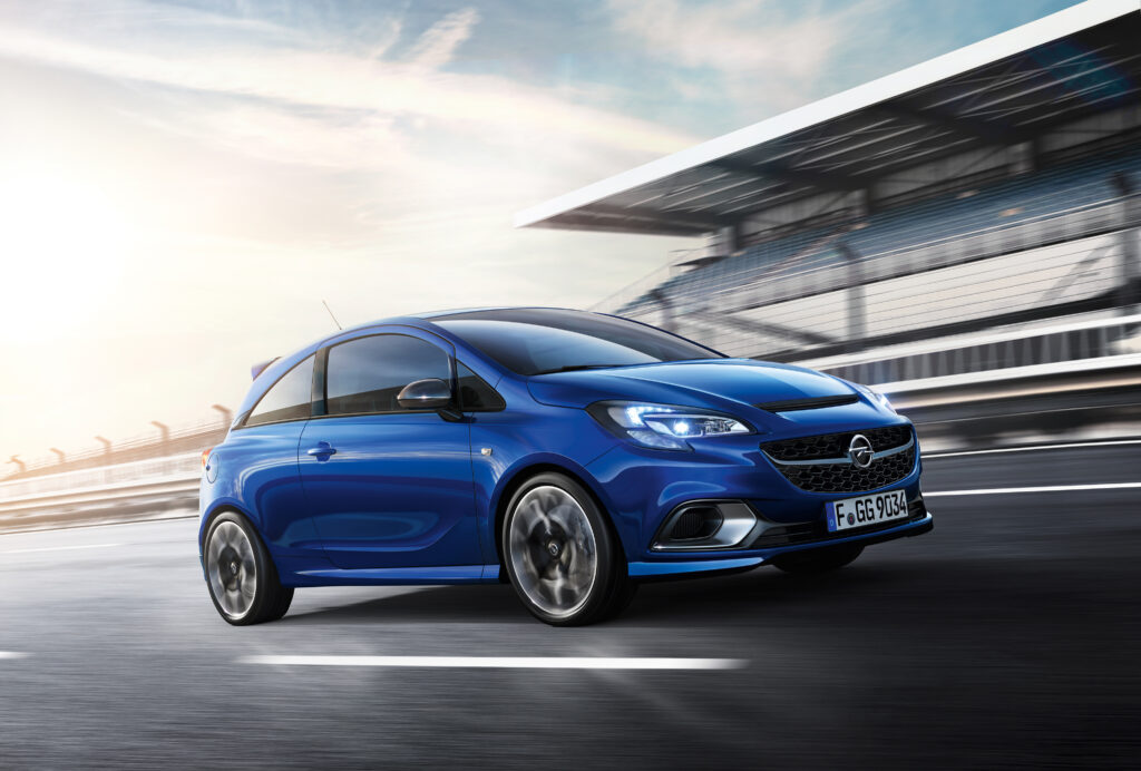 Sleek Blue Opel Corsa on Racetrack: Dynamic Side View Wallpaper