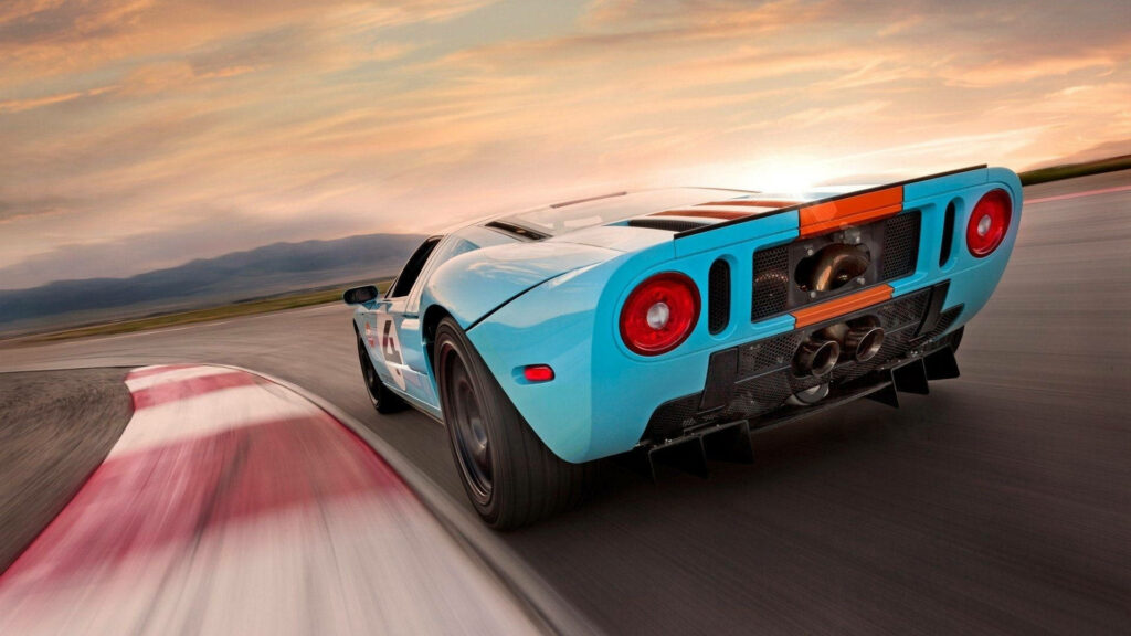 Blue sports car speeding on racetrack at sunset high performance driving dynamic motion wallpaper