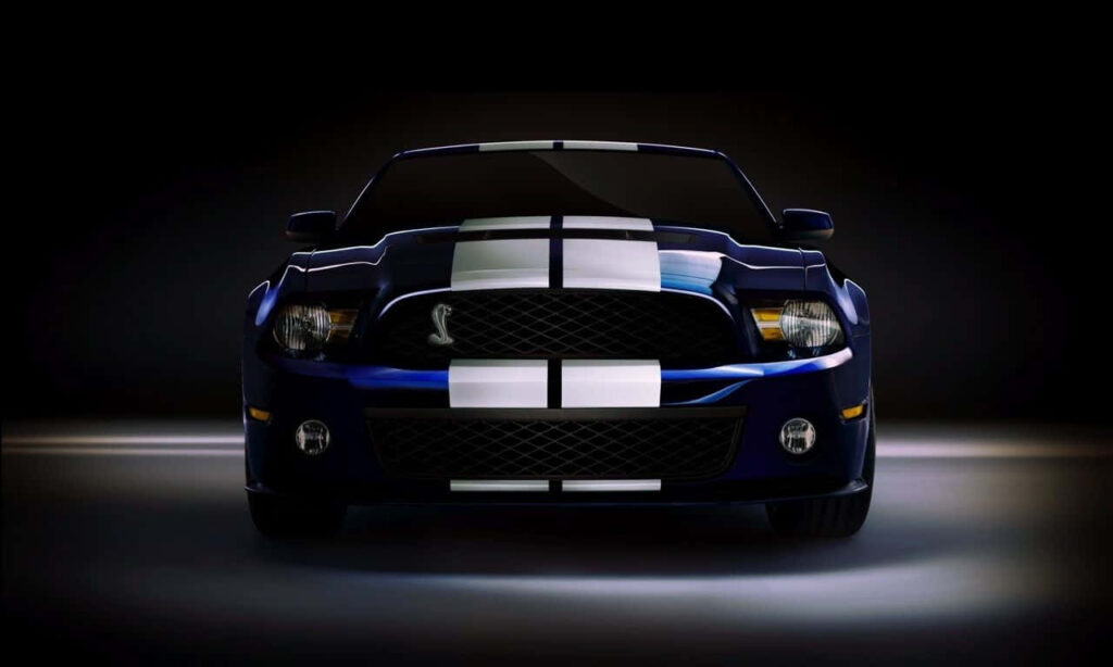 Blue sports car with white racing stripes under dramatic lighting showcasing sleek design Wallpaper