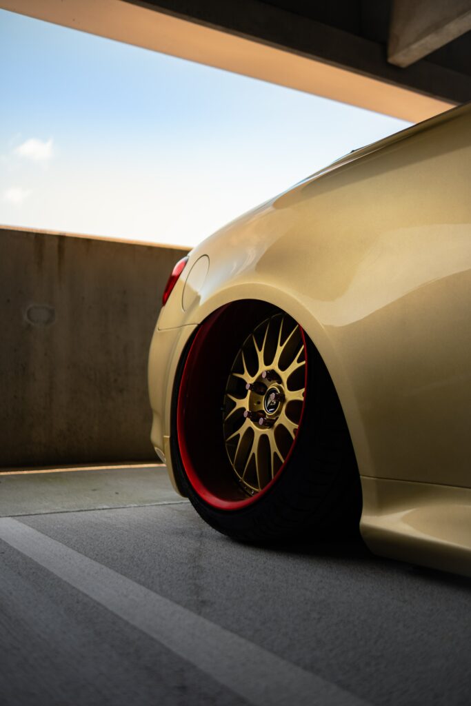 Stunning Car with Custom Gold Rims in Sunlit Parking Structure Wallpaper
