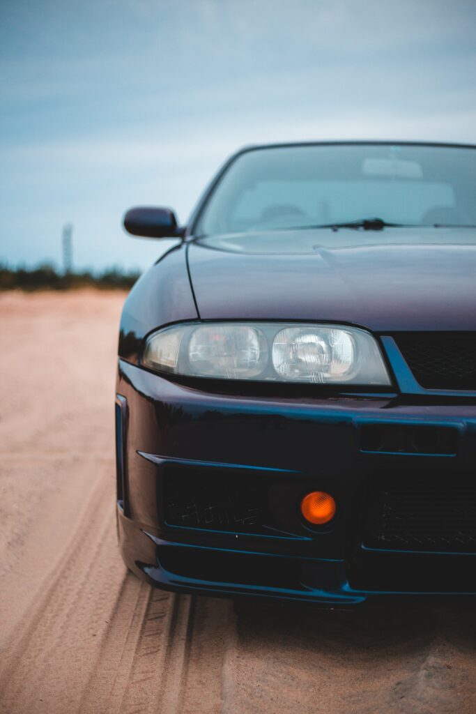 Sleek Car Front View with Glossy Bumper and Sandy Background Wallpaper