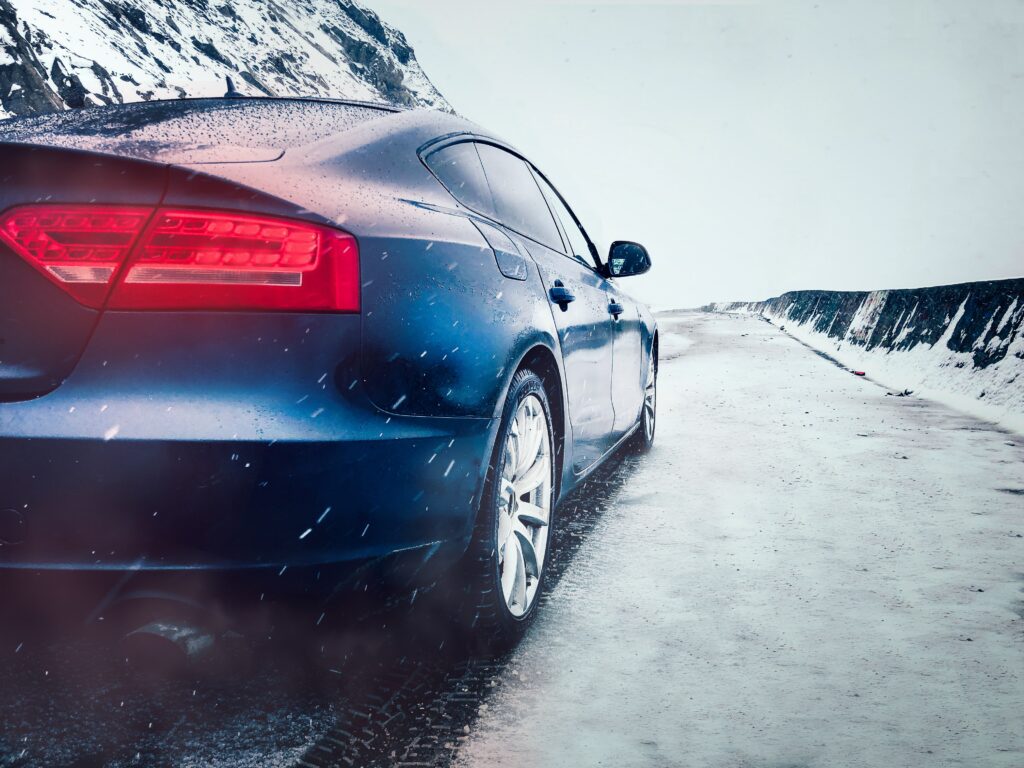 Sleek Car in Snowy Landscape: Dynamic Movement & Illuminated Headlights Wallpaper