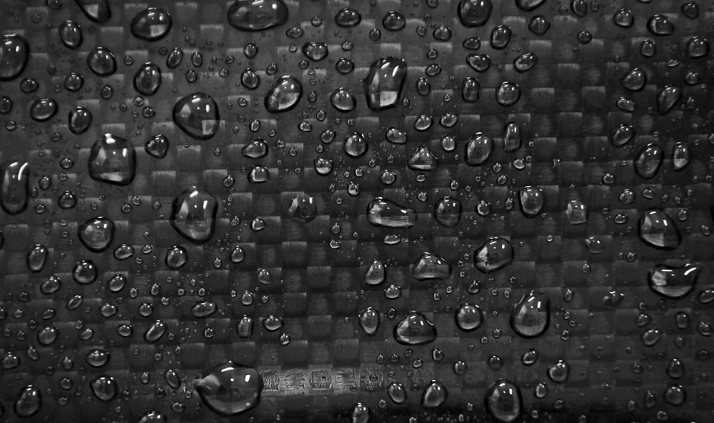 High-resolution carbon fiber texture wallpaper with water droplets and subtle light reflections