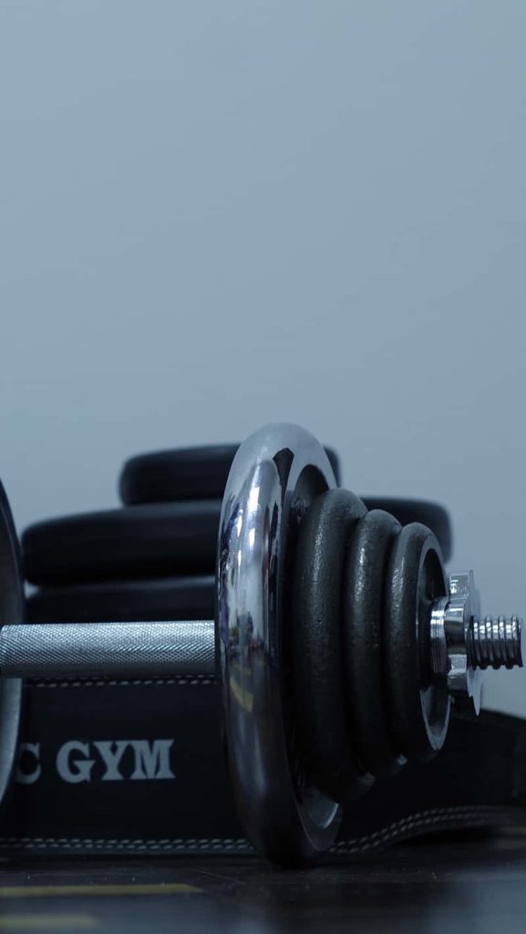 Close-up of chrome dumbbell on black weightlifting belt fitness iPhone lock screen wallpaper