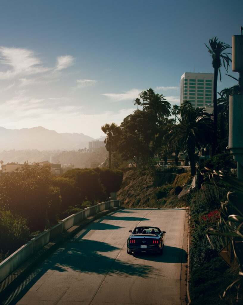Convertible Cruise: Sunlit Road, Palm Trees & Mountain Backdrop Wallpaper