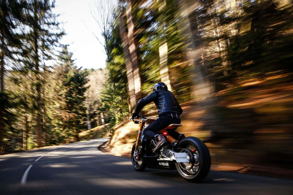 Electric bike speeding on winding forest road with autumn colors and rider in black gear Wallpaper