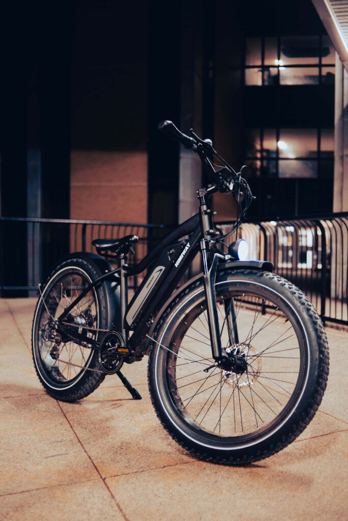 Sleek electric bike with chunky tires illuminated under urban lights in a nighttime city scene Wallpaper