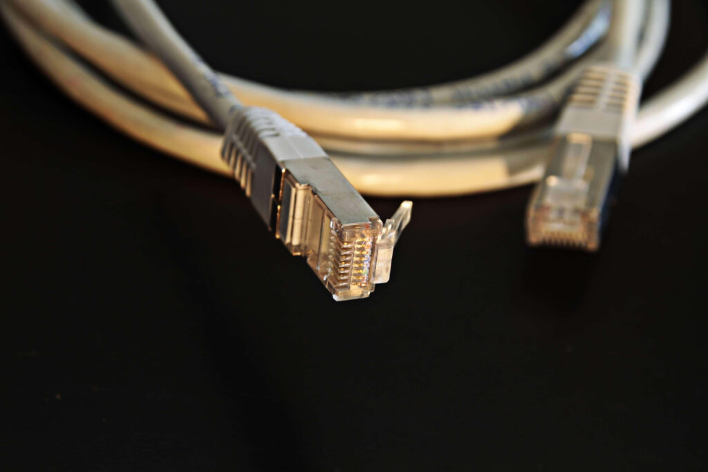 Close-up of gray Ethernet cables with clear connectors on dark background symbolizing connectivity Wallpaper