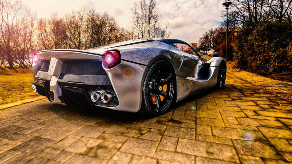 Rear view of sleek Ferrari on sunlit paved road showcasing bold design and power wallpaper