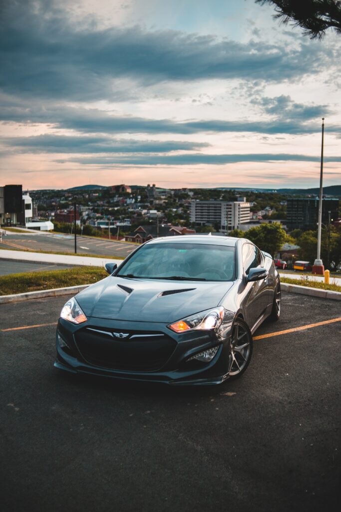 Sleek Genesis Sports Car Wallpaper with Cityscape Background