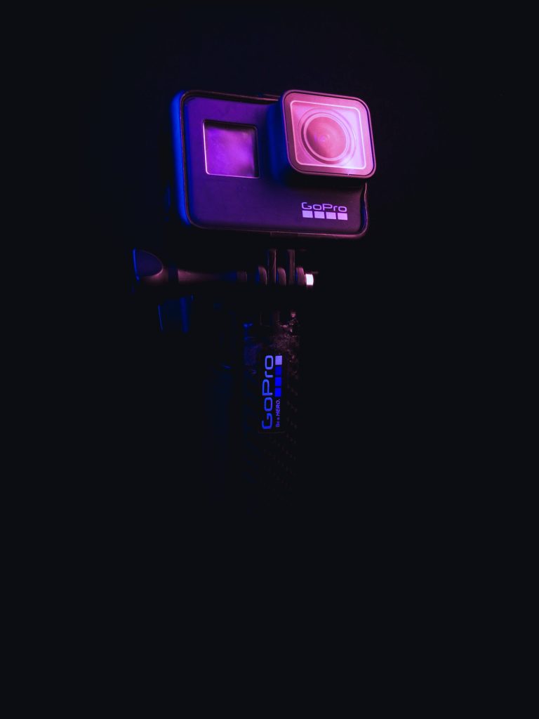 GoPro action camera wallpaper with neon purple and blue rim lighting on black background
