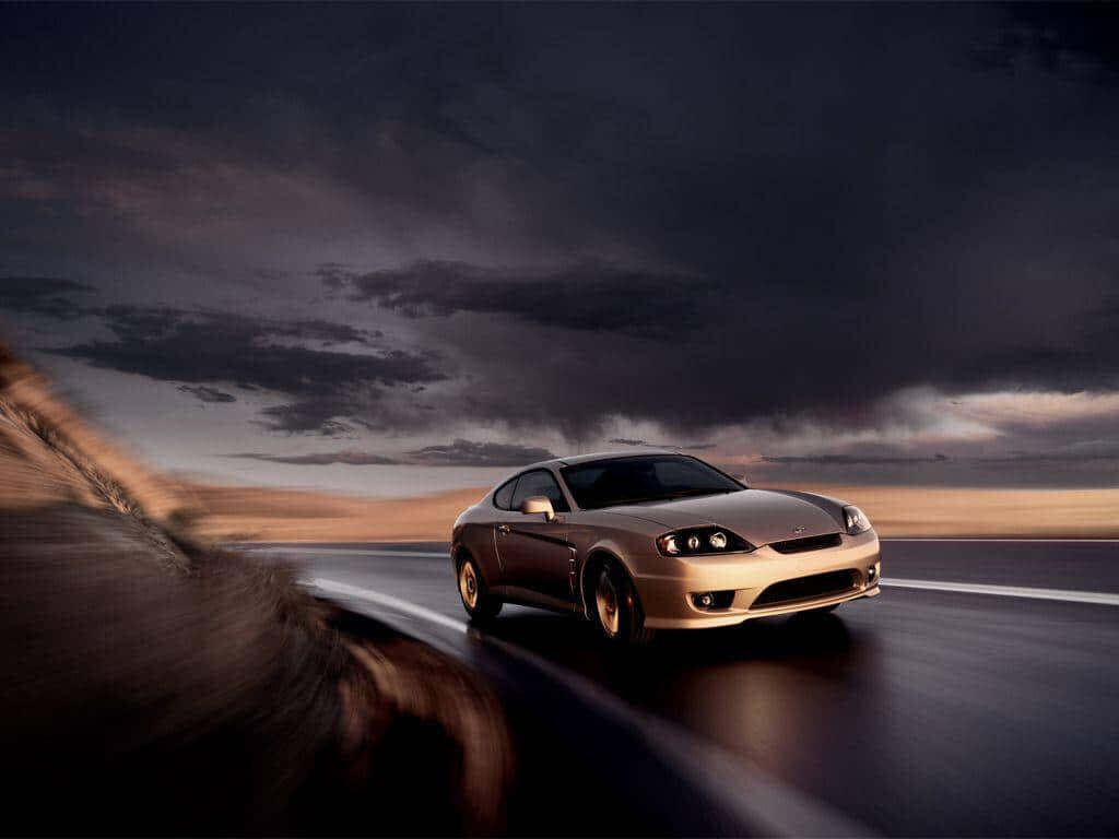 Sleek gold car speeding on winding road under dramatic cloudy night sky adventure wallpaper