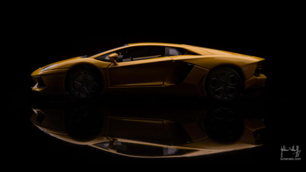 Glossy gold sports car with sharp lines and dramatic reflection in dark wallpaper background
