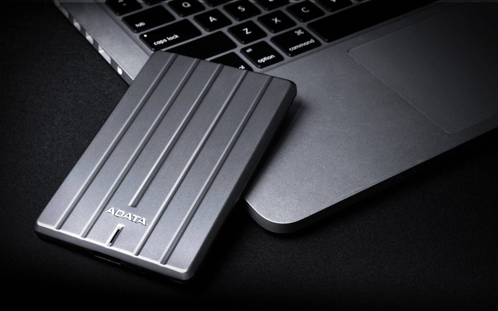 Sleek gray ADATA external hard drive on modern laptop keyboard with soft lighting texture Wallpaper