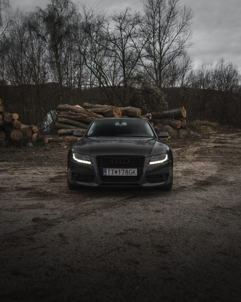 Sleek Gray Audi Wallpaper: Dramatic Front View with Rustic Background