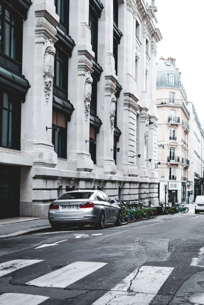 Sleek Gray BMW Amidst Historic Buildings and Vibrant City Setting Wallpaper