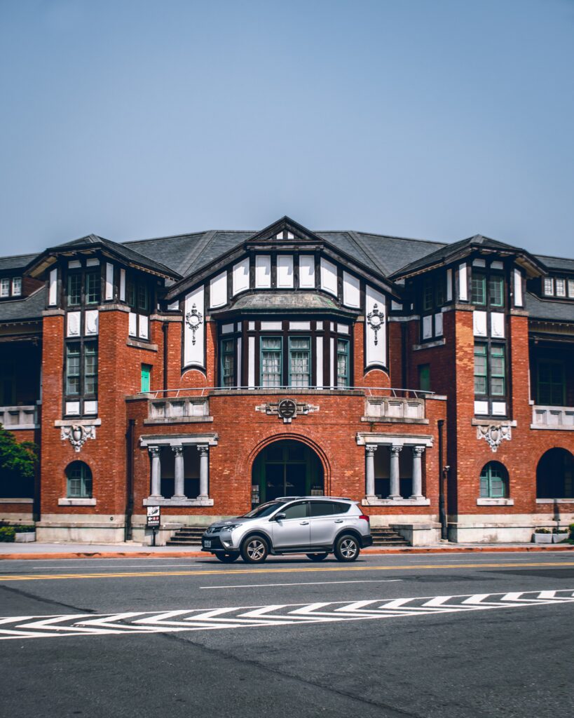 Sleek Gray Car Against Classic Brick Architecture - Wallpaper Background