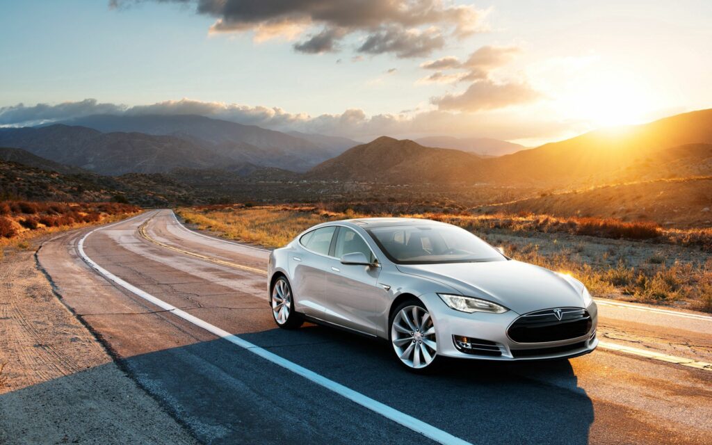 Sleek Gray Tesla Model S at Sunset: Scenic Mountain Road Wallpaper