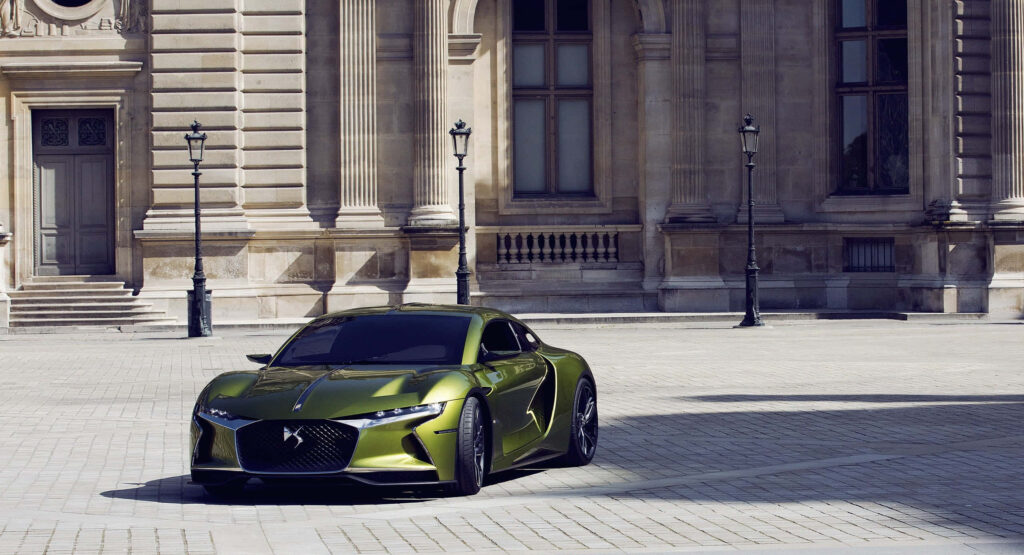 Green DS Automobiles car with sleek modern design and metallic finish against grand architecture Wallpaper