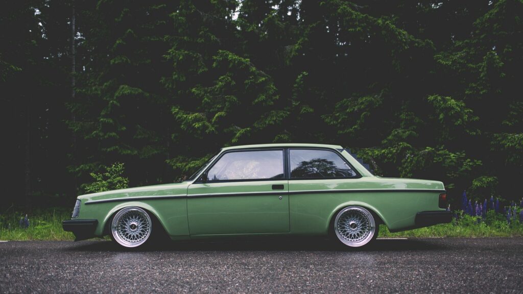 Sleek Green Volvo 242 in Lush Forest - Classic Car Wallpaper