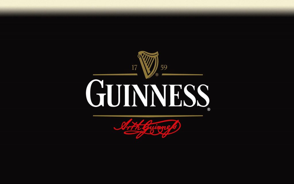 Guinness logo wallpaper with gold Irish harp white lettering and red signature on black background