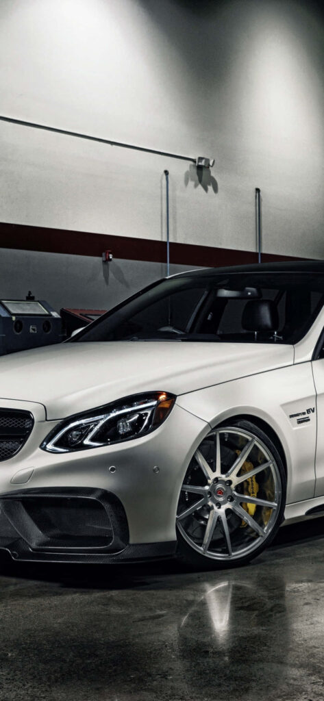 Light grey Mercedes-Benz E-Class with aggressive front and sporty alloy wheels in stylish indoor setting Wallpaper