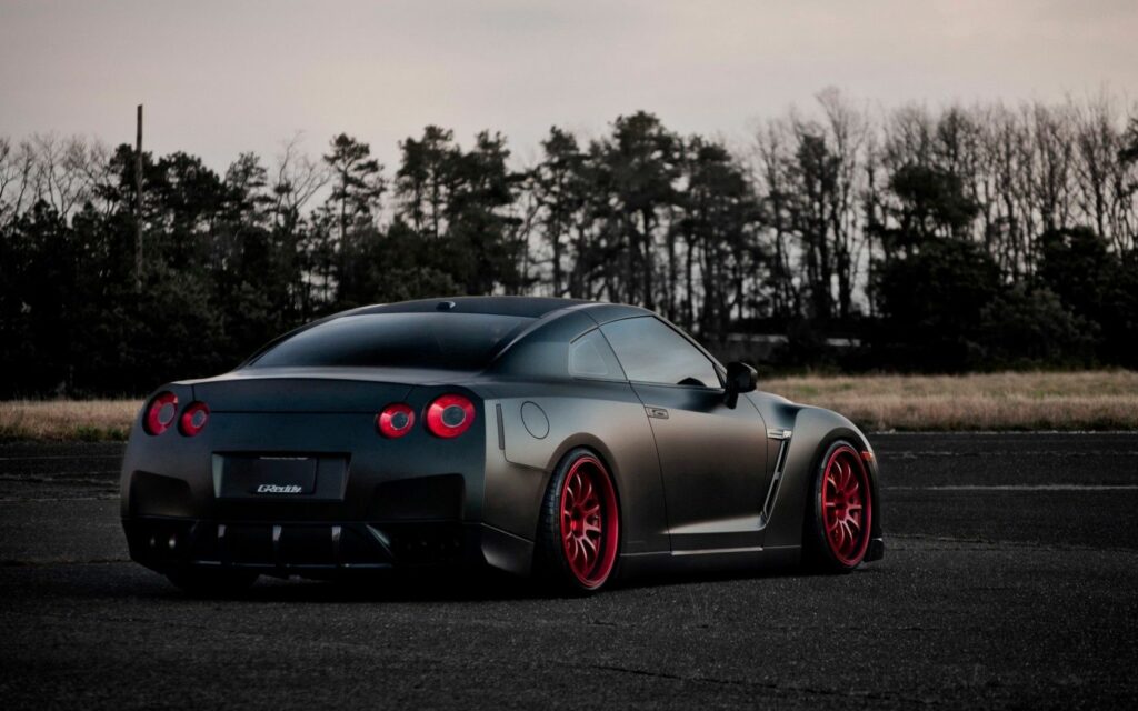 Matte Black Nissan GT-R in Nature: Rear View with Red Tuning Accents Wallpaper