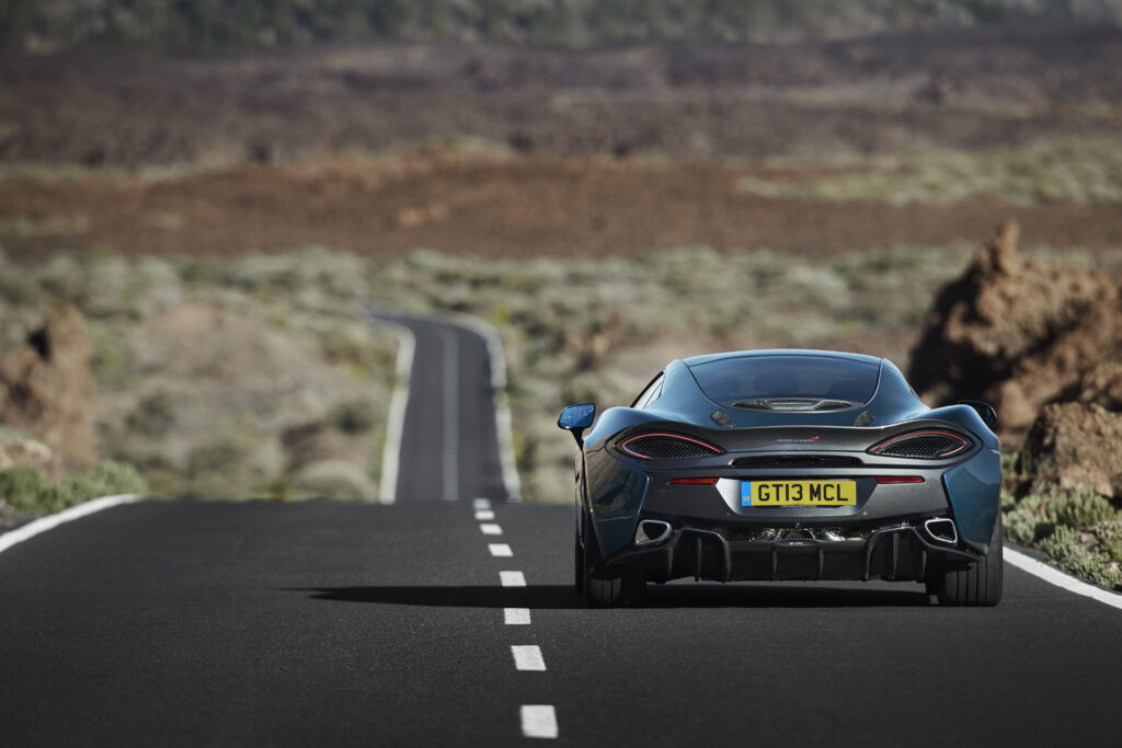 Stunning McLaren 570GT Rear View Wallpaper in Rugged Landscape