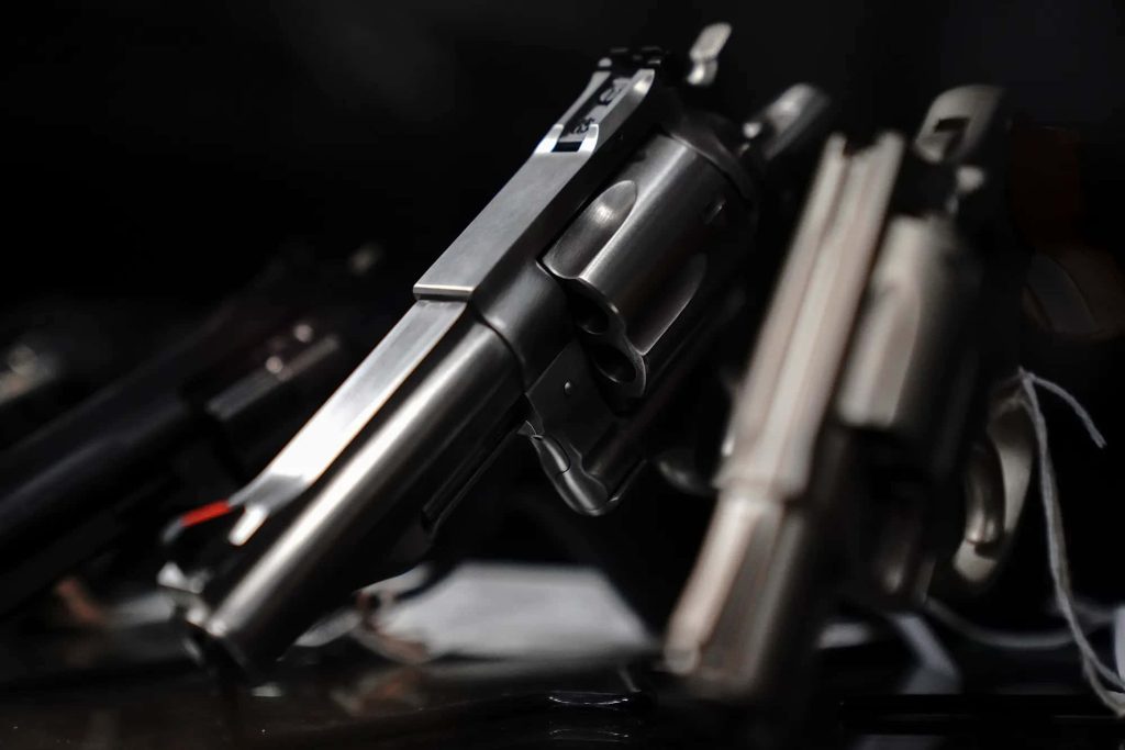 Close-up of sleek metallic revolvers with dramatic lighting on dark moody background wallpaper