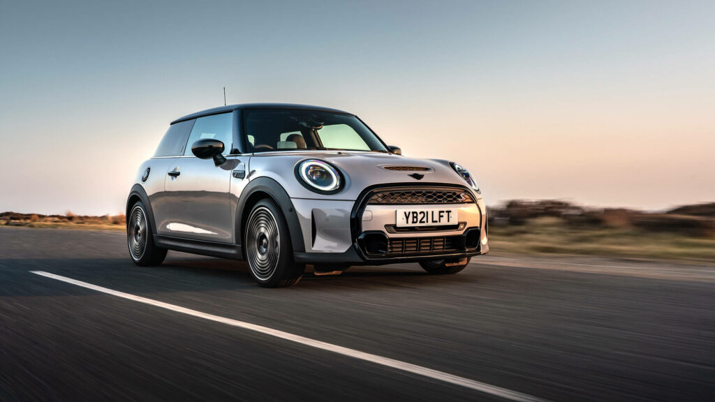 Mini gray car driving on open road at sunset with warm light scenic wallpaper background