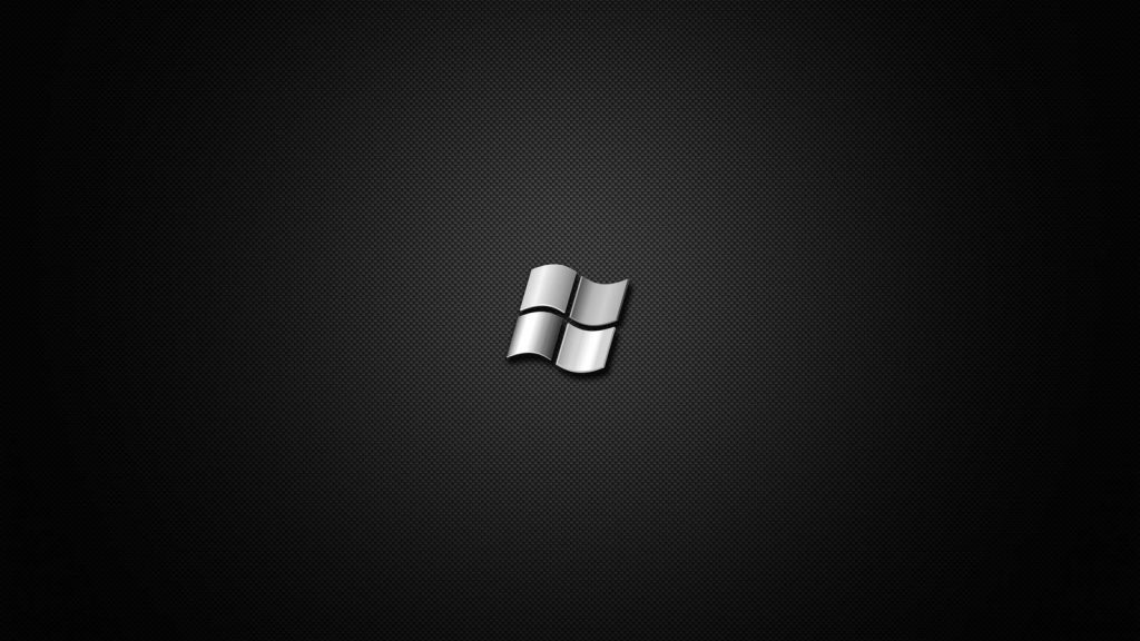 Sleek silver Windows logo on textured black carbon fiber background minimalist wallpaper