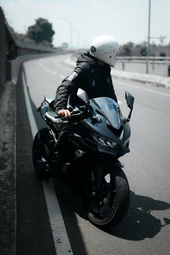 Contemplative Rider on Black Motorcycle - Stylish Wallpaper Background